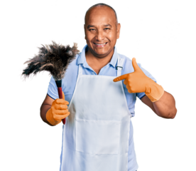 Hispanic middle age man wearing apron holding cleaning duster pointing finger to one self smiling happy and proud