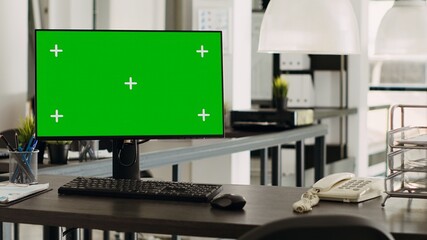 Greenscreen desktop in coworking space pc placed on workstation, open floor plan business office. Computer monitor showing isolated chromakey template with blank mockup display.