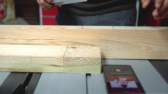 A shot of a woodworker measuring and marking his cuts on a board of pine
