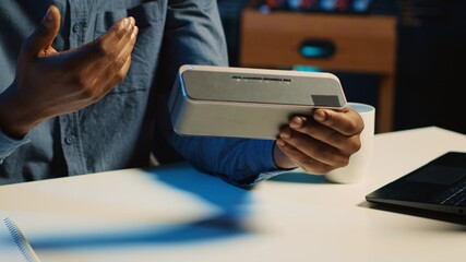 Close up shot of portable speaker used by content creator doing technology reviews for his online platforms channel. Influencer presents music playing device to his audience