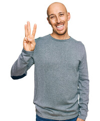 Bald man with beard wearing casual clothes showing and pointing up with fingers number three while smiling confident and happy.