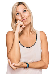 Fototapeta premium Middle age caucasian woman wearing casual clothes with hand on chin thinking about question, pensive expression. smiling with thoughtful face. doubt concept.