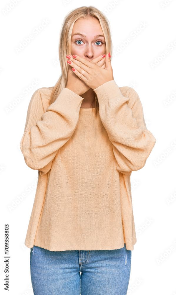 Wall mural young blonde girl wearing casual clothes shocked covering mouth with hands for mistake. secret conce