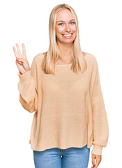 Young blonde girl wearing casual clothes showing and pointing up with fingers number three while smiling confident and happy.