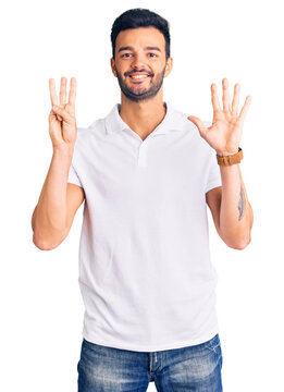 Young handsome hispanic man wearing casual clothes showing and pointing up with fingers number eight while smiling confident and happy.