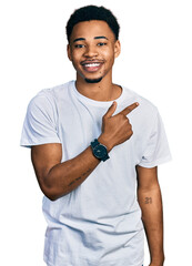 Fototapeta premium Young african american man wearing casual white t shirt cheerful with a smile on face pointing with hand and finger up to the side with happy and natural expression
