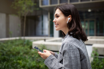 young lady enjoying music via earbuds and mobile phone outside