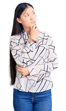 Young beautiful chinese woman wearing casual shirt thinking worried about a question, concerned and nervous with hand on chin