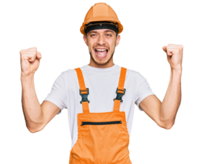 Hispanic young man wearing handyman uniform and safety hardhat screaming proud, celebrating victory and success very excited with raised arms