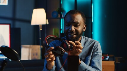 African american technology internet star filming review of newly released RGB lit keyboard, mouse and headphones, giving audience feedback about gaming capabilities, doing endorsement