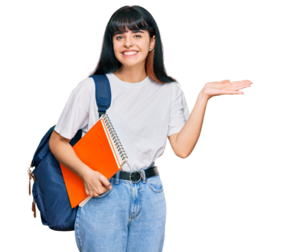 Young hispanic girl wearing student backpack and holding book celebrating victory with happy smile and winner expression with raised hands