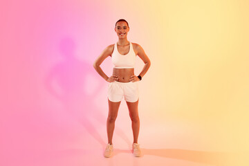 A confident female athlete stands with hands on hips in white sportswear, her shadow cast