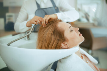 40 years old hair salon employee in hair studio washing hair