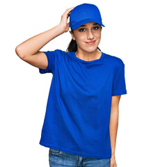 Young hispanic girl wearing delivery courier uniform confuse and wonder about question. uncertain with doubt, thinking with hand on head. pensive concept.