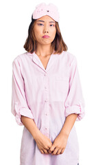 Young beautiful chinese girl wearing sleep mask and pajama depressed and worry for distress, crying angry and afraid. sad expression.