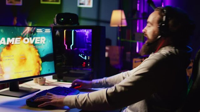 Angry gamer raging in frustration after losing level while playing spaceship videogame. Upset player furiously hitting table, getting flying spacecraft destroyed in game, receiving game over message