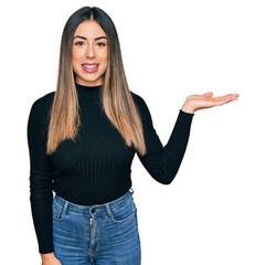 Young hispanic woman wearing casual clothes smiling cheerful presenting and pointing with palm of hand looking at the camera.