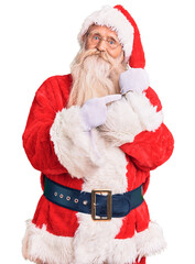 Old senior man with grey hair and long beard wearing traditional santa claus costume in hurry pointing to watch time, impatience, looking at the camera with relaxed expression