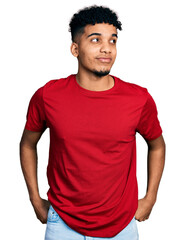 Fototapeta premium Young african american man wearing casual red t shirt smiling looking to the side and staring away thinking.