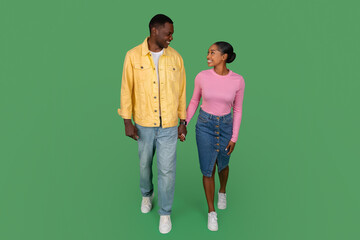 Happy millennial black man and woman holding hands and walking