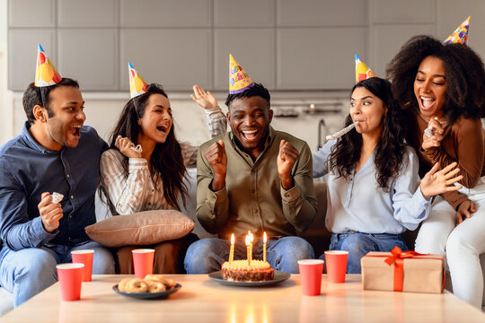Happy multiracial students celebrating birthday of black guy in kitchen