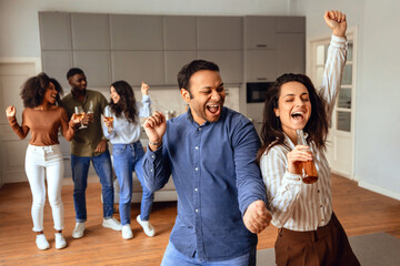 Energetic multicultural friends singing and dancing with joy in kitchen