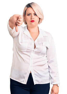 Young blonde plus size woman wearing casual shirt looking unhappy and angry showing rejection and negative with thumbs down gesture. bad expression.