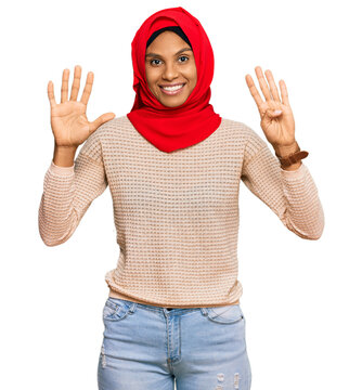 Young african american woman wearing traditional islamic hijab scarf showing and pointing up with fingers number nine while smiling confident and happy.
