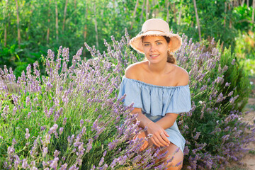 Woman in blue dress sitting beside lavender shrub and smiling