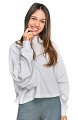 Young brunette woman wearing casual turtleneck sweater looking confident at the camera with smile with crossed arms and hand raised on chin. thinking positive.