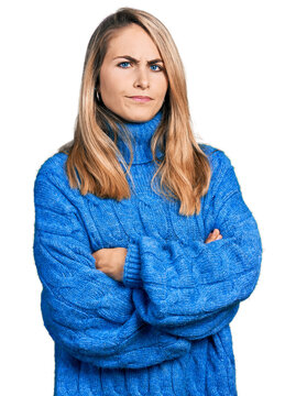 Young blonde woman wearing casual sweater skeptic and nervous, disapproving expression on face with crossed arms. negative person.