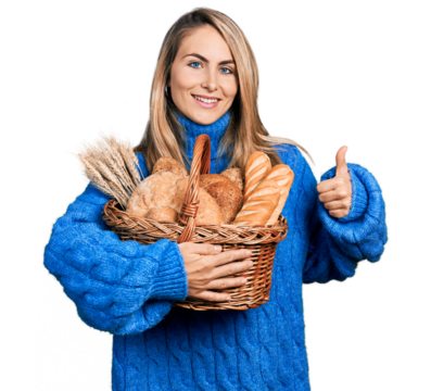 Young blonde woman holding wicker basket with bread smiling happy and positive, thumb up doing excellent and approval sign