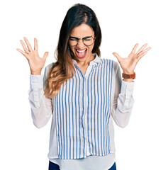 Beautiful hispanic woman wearing casual striped shirt celebrating mad and crazy for success with...