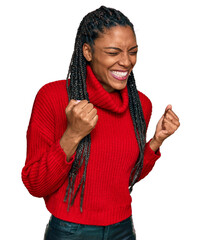African american woman wearing casual winter sweater excited for success with arms raised and eyes...