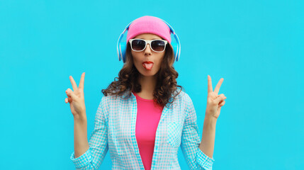 Portrait of stylish modern happy young woman listening to music with headphones wearing colorful...
