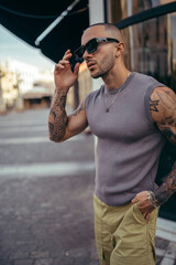 Hombre joven musculado y tatuado posando en la calle con ropa basica urbana 