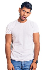 Fototapeta premium Young latin man wearing casual clothes in shock face, looking skeptical and sarcastic, surprised with open mouth