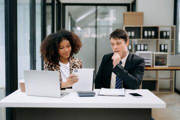 Two business workers talking on the smartphone and using laptop at the office...