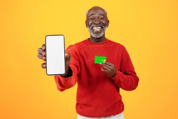 Smiling senior african american man show credit card and smartphone with empty screen