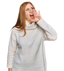 Young irish woman wearing casual winter sweater shouting and screaming loud to side with hand on...