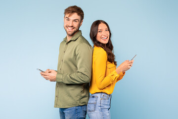 Back-to-back couple with phones, smiling and engaged in digital