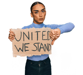 Hispanic transgender man wearing make up and long hair holding united we stand banner with angry face, negative sign showing dislike with thumbs down, rejection concept