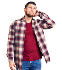 Young handsome man wearing casual shirt confuse and wondering about question. uncertain with doubt,...