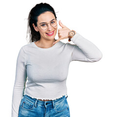 Young hispanic woman wearing casual clothes smiling doing phone gesture with hand and fingers like...