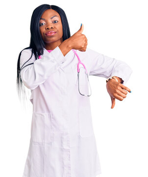 Young african american woman wearing doctor stethoscope doing thumbs up and down, disagreement and agreement expression. crazy conflict