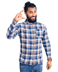Young arab man wearing casual clothes smiling and confident gesturing with hand doing small size sign with fingers looking and the camera. measure concept.