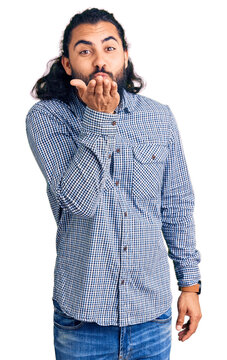 Young arab man wearing casual clothes looking at the camera blowing a kiss with hand on air being lovely and sexy. love expression.