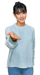 Young hispanic woman wearing casual clothes smiling cheerful offering palm hand giving assistance and acceptance.