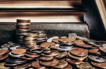 Photo of old brown antique books stacked on a pile of world coins.