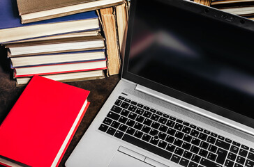 Photo of modern laptop or notebook laying on table with old antique books.